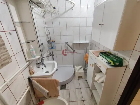 Manje kupatilo sa tuš kabinom, umivaonikom i belim ormarićima. - image 8