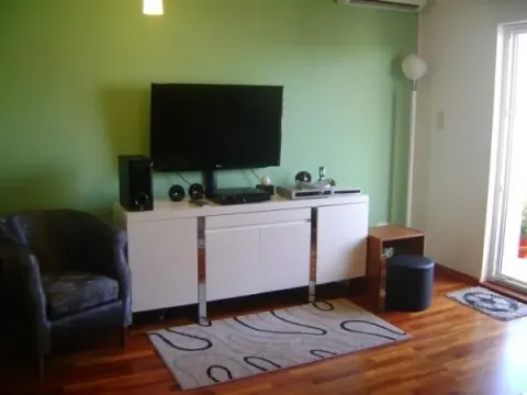 Dnevna soba sa zelenim zidom i komodom za televizor. - image 4