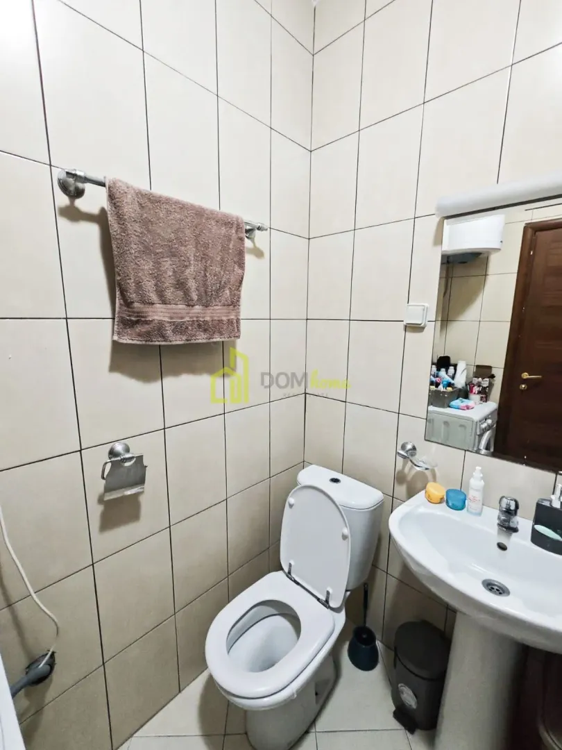 Smaller bathroom with a washbasin, toilet bowl and mirror.