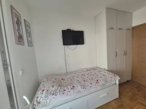 Manja spavaća soba sa krevetom, ormarom i zidnim televizorom. - image 13