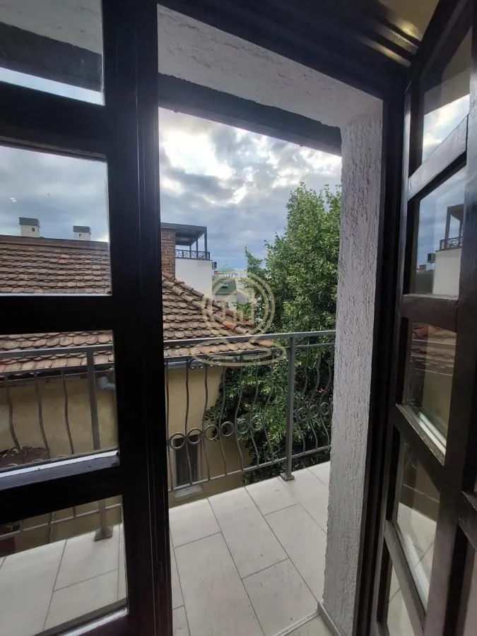 Pogled sa balkona na okolne zgrade i zelenilo.