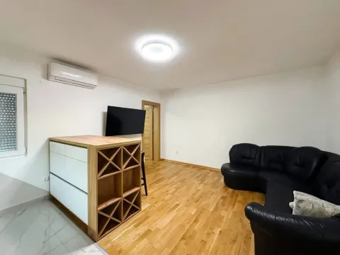 Living room with a black sectional sofa, wooden floor, and wall-mounted TV. - image 4