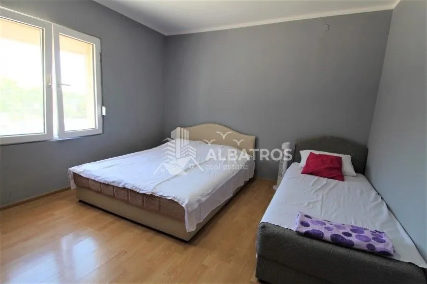 Bedroom with a double bed and an additional single bed, grey walls, and wooden flooring.