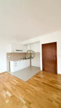 Manja bijela kuhinja u sklopu prostorije sa drvenim podom i drvenim vratima. - image 5