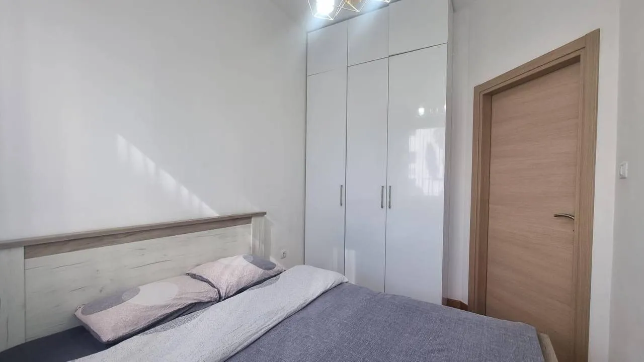 Namještena spavaća soba sa bračnim krevetom i ugradnim ormarom.