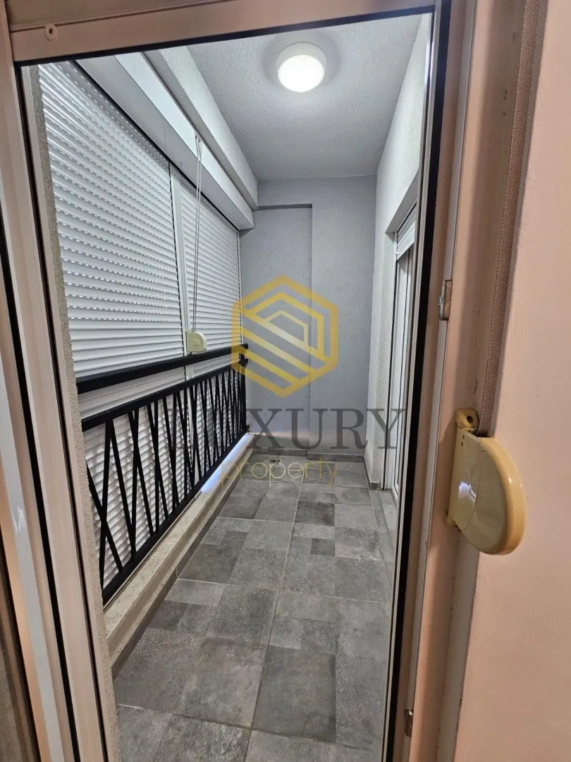 Zastakljeni balkon sa pločicama i ogradom.