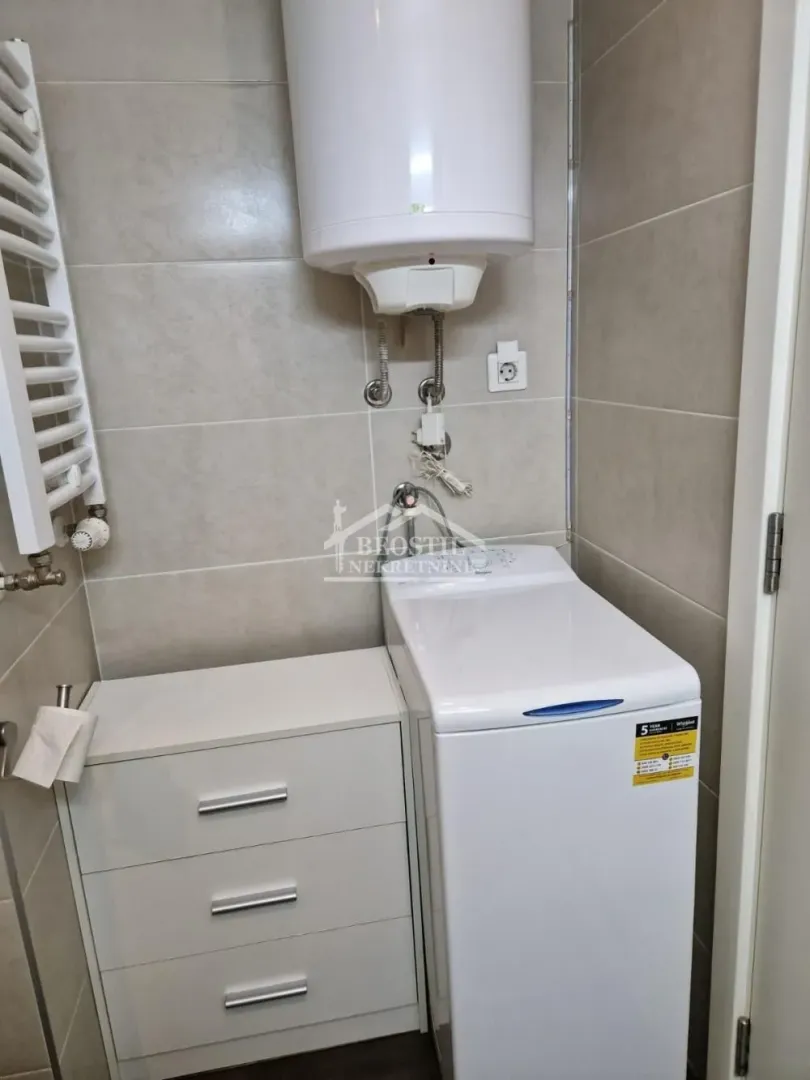 Bathroom equipped with a washing machine, water heater, and a white chest of drawers.