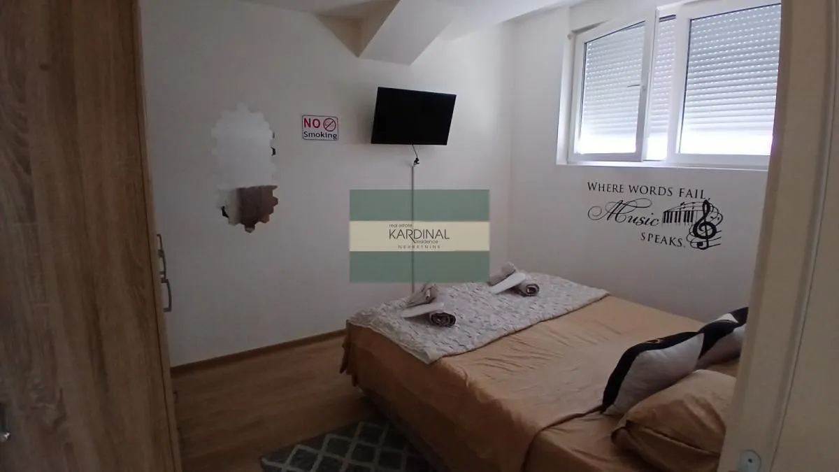 Nameštena spavaća soba sa bračnim krevetom i prozorom.