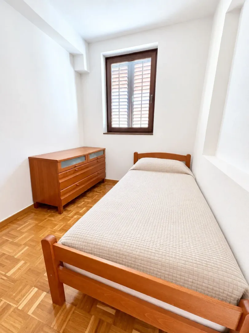 Small bedroom with a bed and wooden chest of drawers.