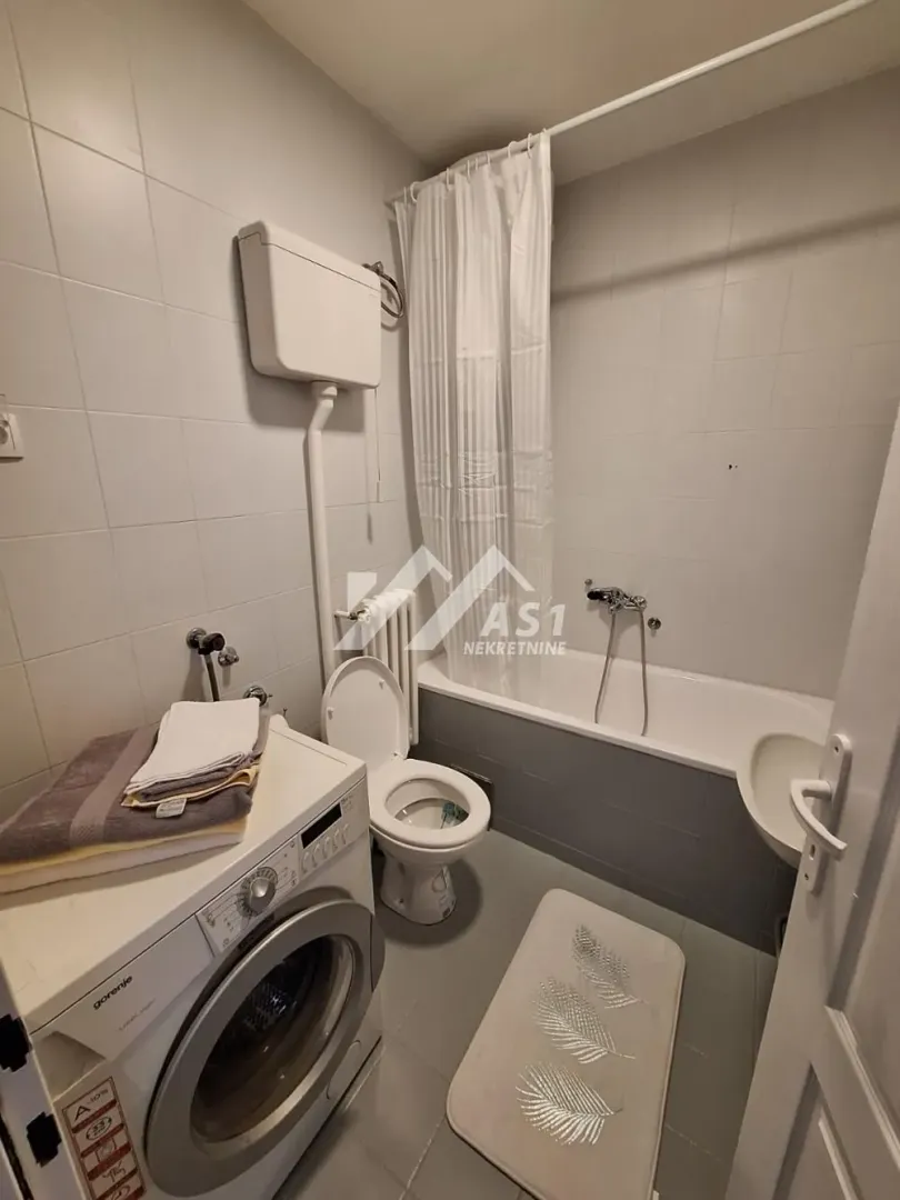 Small bathroom equipped with a bathtub, toilet, sink, and washing machine.