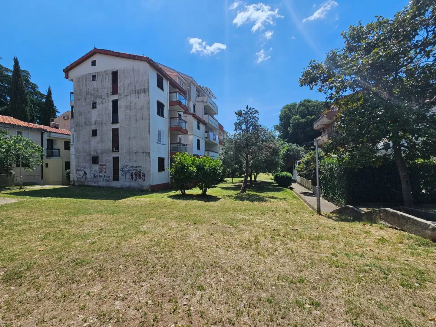 Pogled na stambenu zgradu i zelenu površinu u dvorištu.