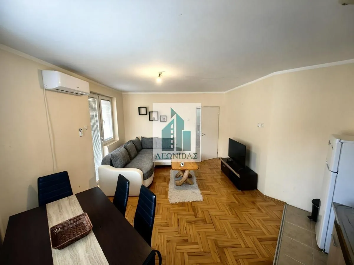 Living room with sofa, dining table, and air conditioning.