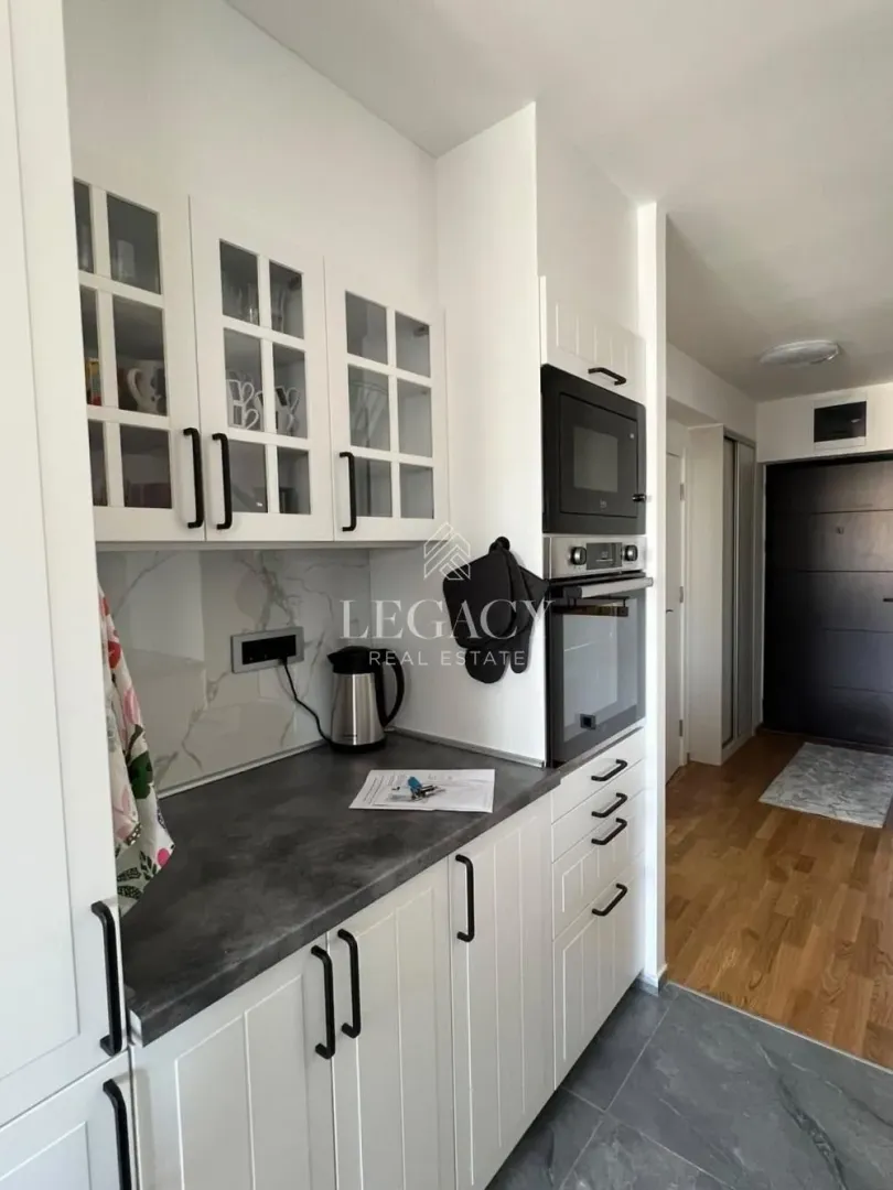 Small white kitchen with a dark countertop and built-in appliances.