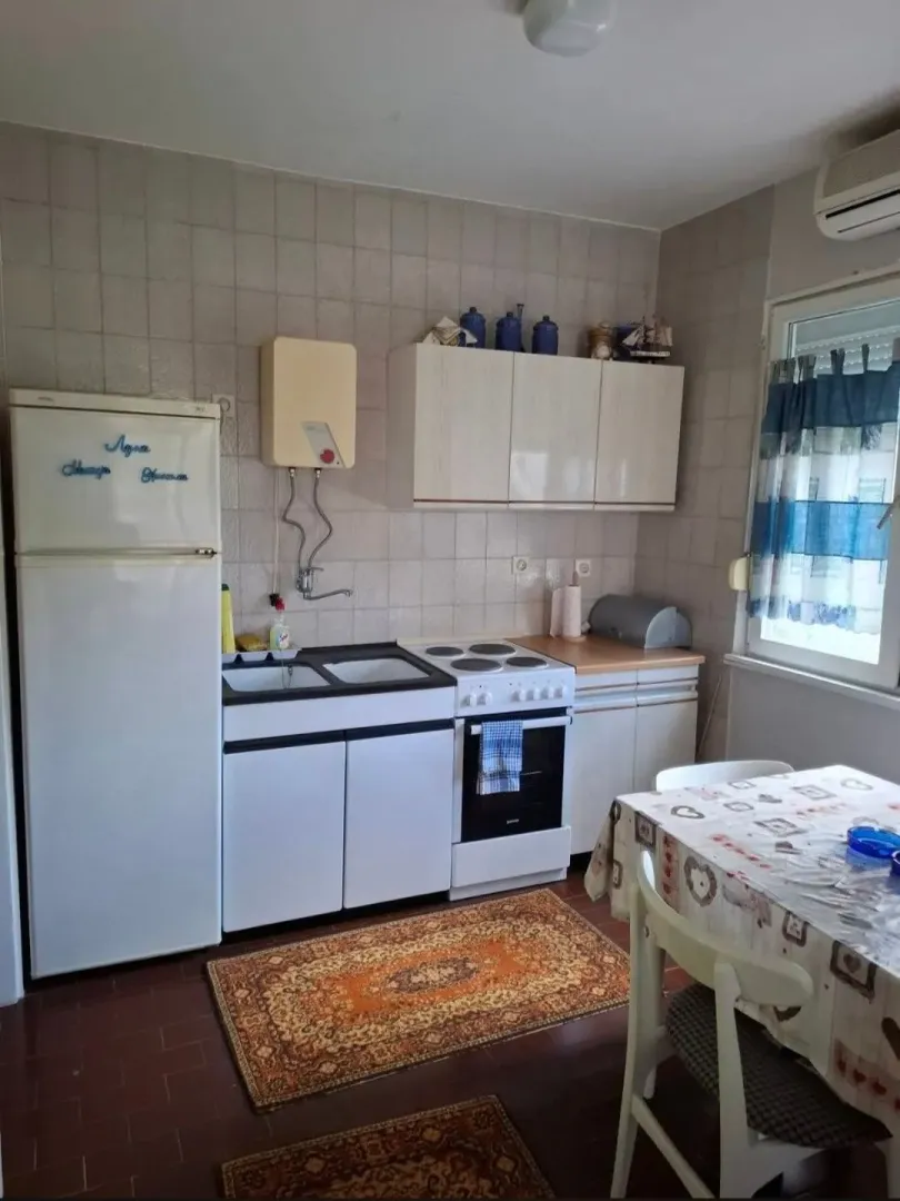 Manja kuhinja sa trpezarijskim stolom i osnovnim elementima.
