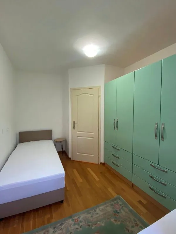 Manja spavaća soba sa krevetom i velikim zelenim ormarom.