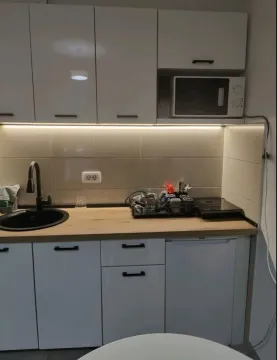 Small white kitchen with wooden countertop and built-in elements. - image 3