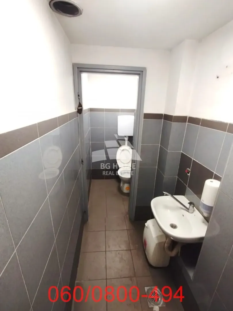 Small tiled bathroom with a sink and a toilet in the background.