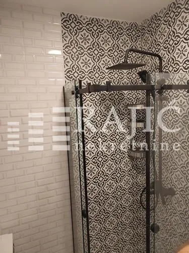 Modern bathroom with a walk-in shower and decorative tiles.
