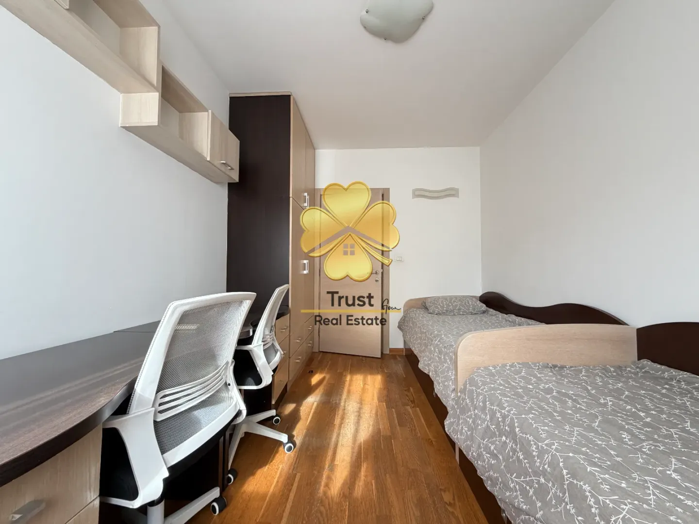 Furnished bedroom with two beds and a desk.