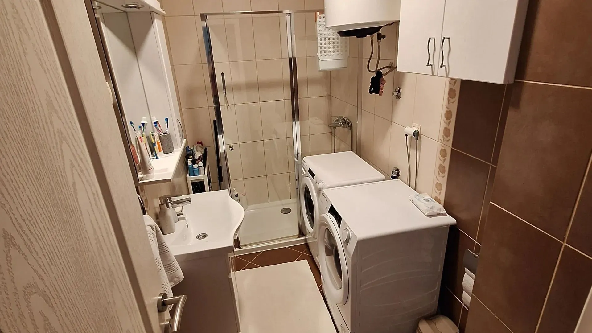 Bathroom equipped with a washbasin, shower cabin, and washing machine.