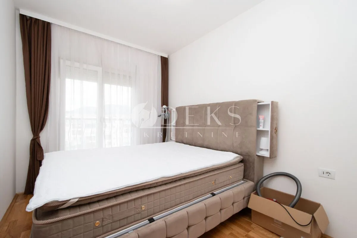 Bedroom with a double bed and a window with white and brown curtains.