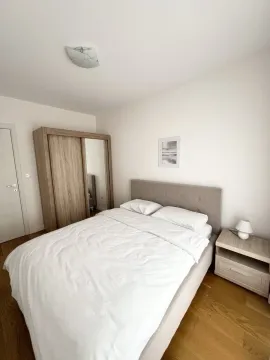Bright bedroom with a double bed, wooden wardrobe, and nightstand. - image 4