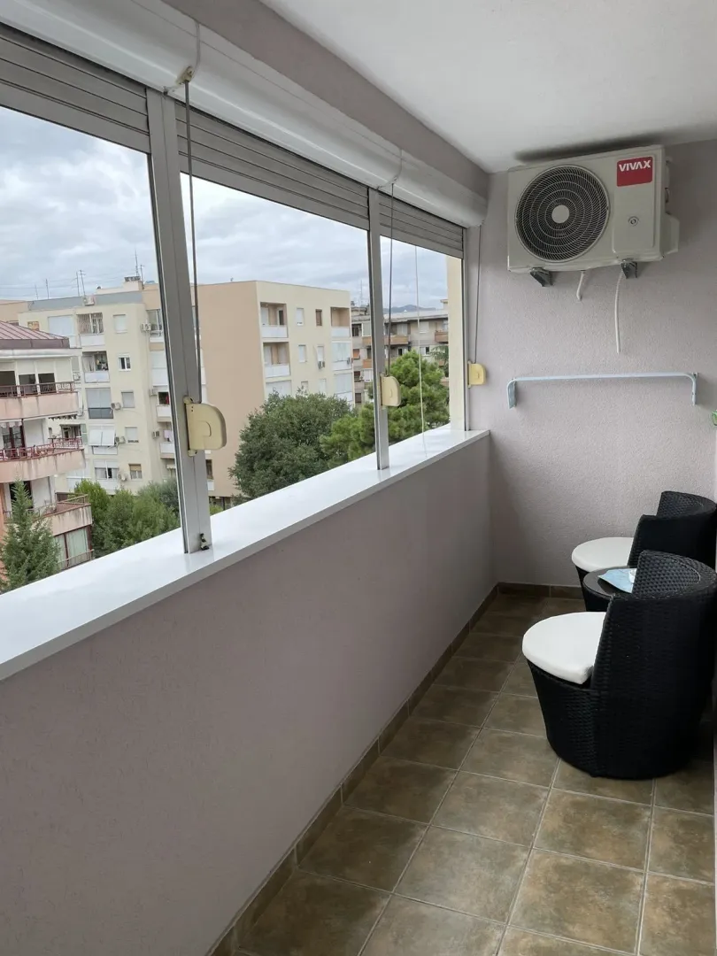 Glazed balcony with outdoor seating and an air conditioning unit.