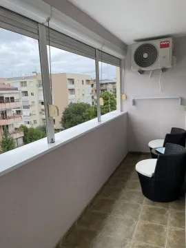 Glazed balcony with outdoor seating and an air conditioning unit. - image 14