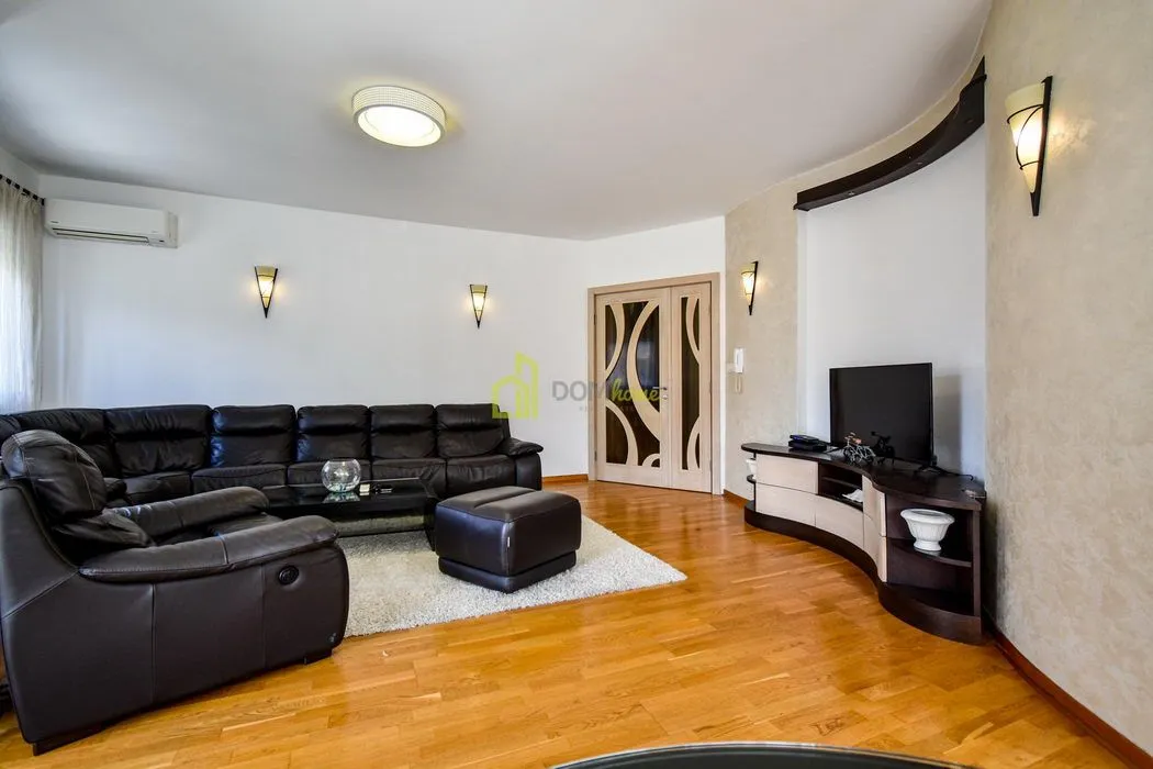 Spacious living room with a black leather sofa and hardwood flooring.
