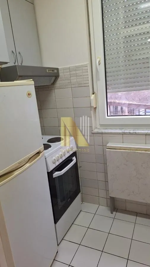 Manja kuhinja sa frižiderom, šporetom i pločicama na zidu.