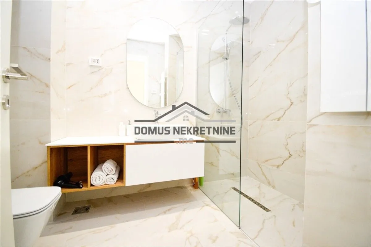 Modernly equipped bathroom with a walk-in shower and marble-look tiles.