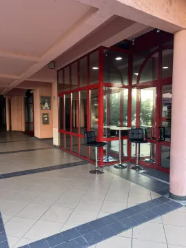 Entrance to a commercial property featuring a red-framed glass facade and bar stools. - image 10