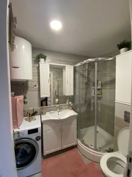 Compact bathroom with a shower cabin, washbasin, toilet, and washing machine. - image 4