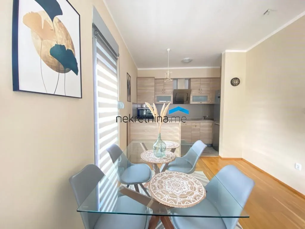 Dining area with a glass table and a view of the kitchen.