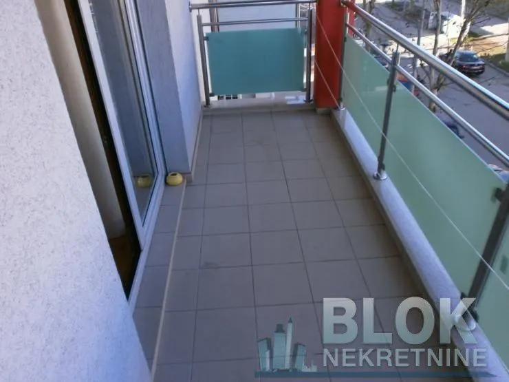 Small tiled balcony with metal railing and glass panels.