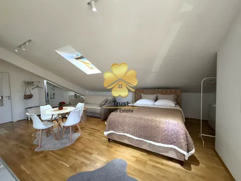 Spacious bedroom with a double bed and a dining table under a sloped ceiling. - image 3