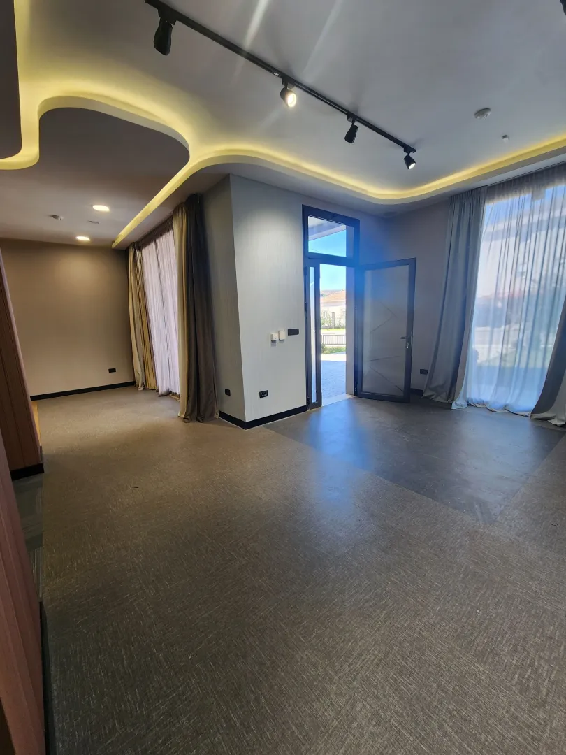 Empty living room with dropped ceiling, recessed lighting and access to the terrace.