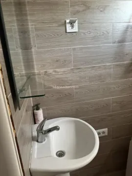 Manje kupatilo sa umivaonikom i zidnim pločicama u dezenu drveta. - image 8