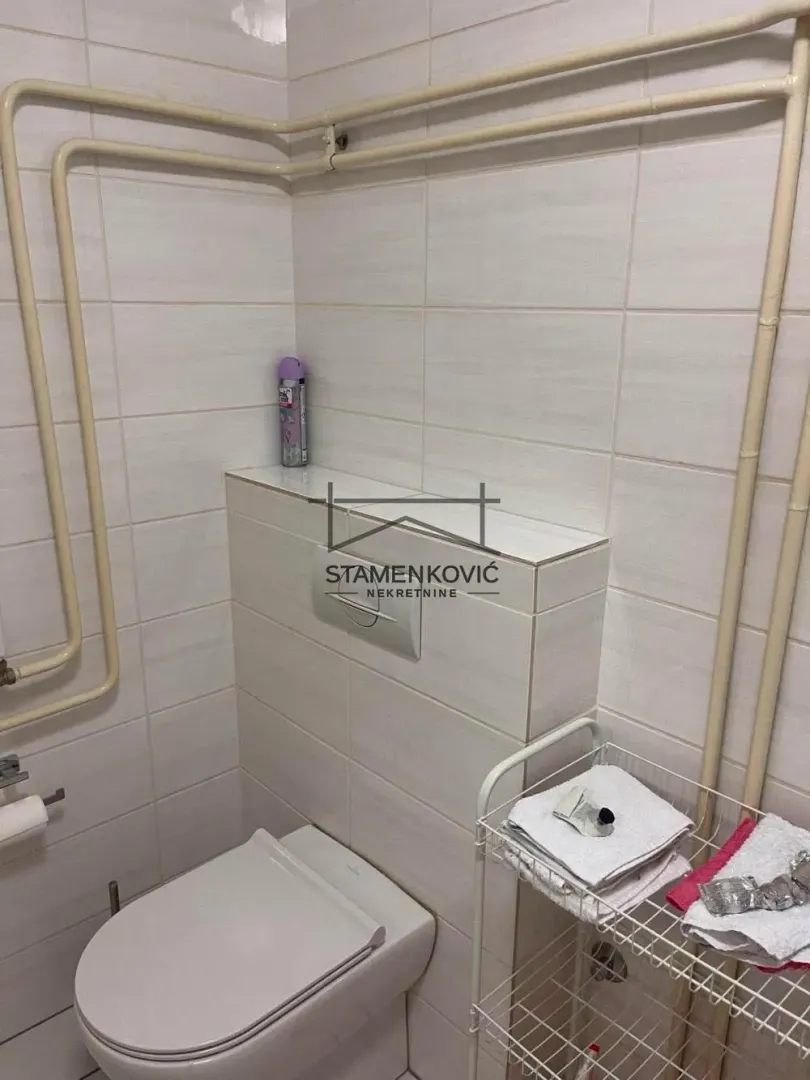 Pogled na kupatilo sa WC šoljom i zidnim pločicama.