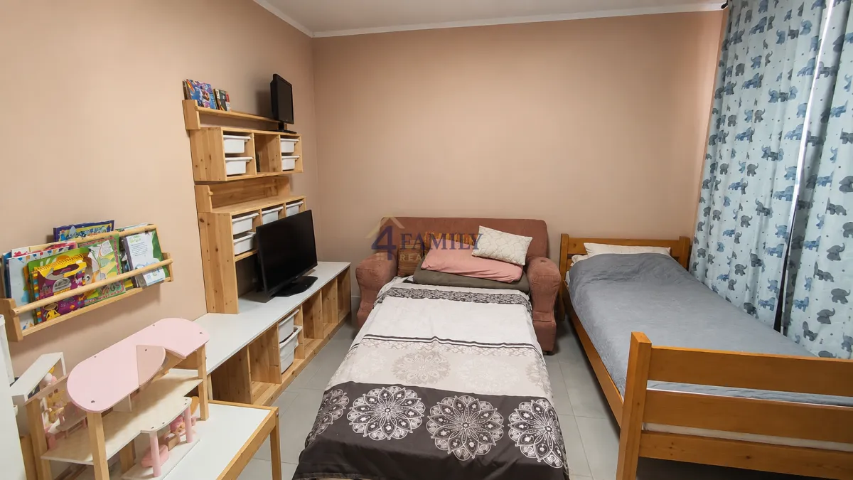 Children's bedroom with two beds and light wood furniture.