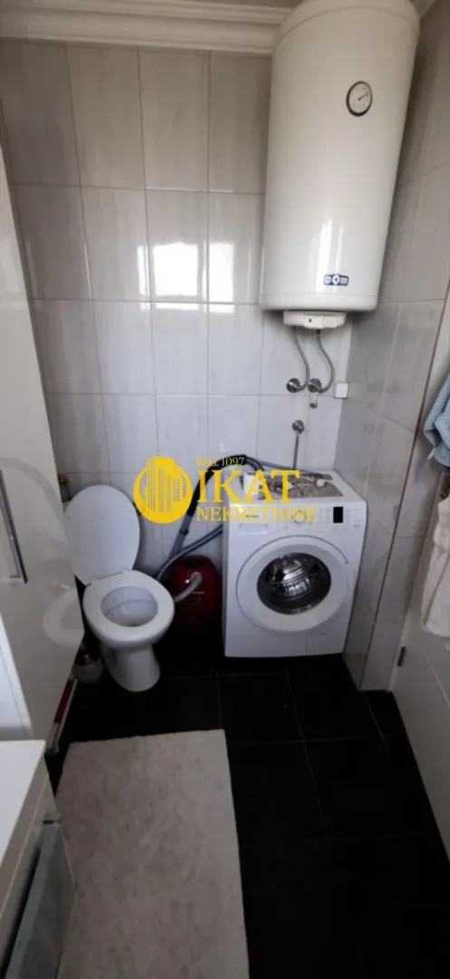 Manje kupatilo sa wc šoljom, veš mašinom i bojlerom.