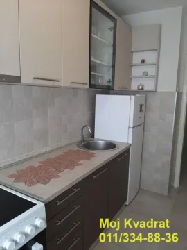 Small equipped kitchen with white and brown cabinetry and appliances. - image 5