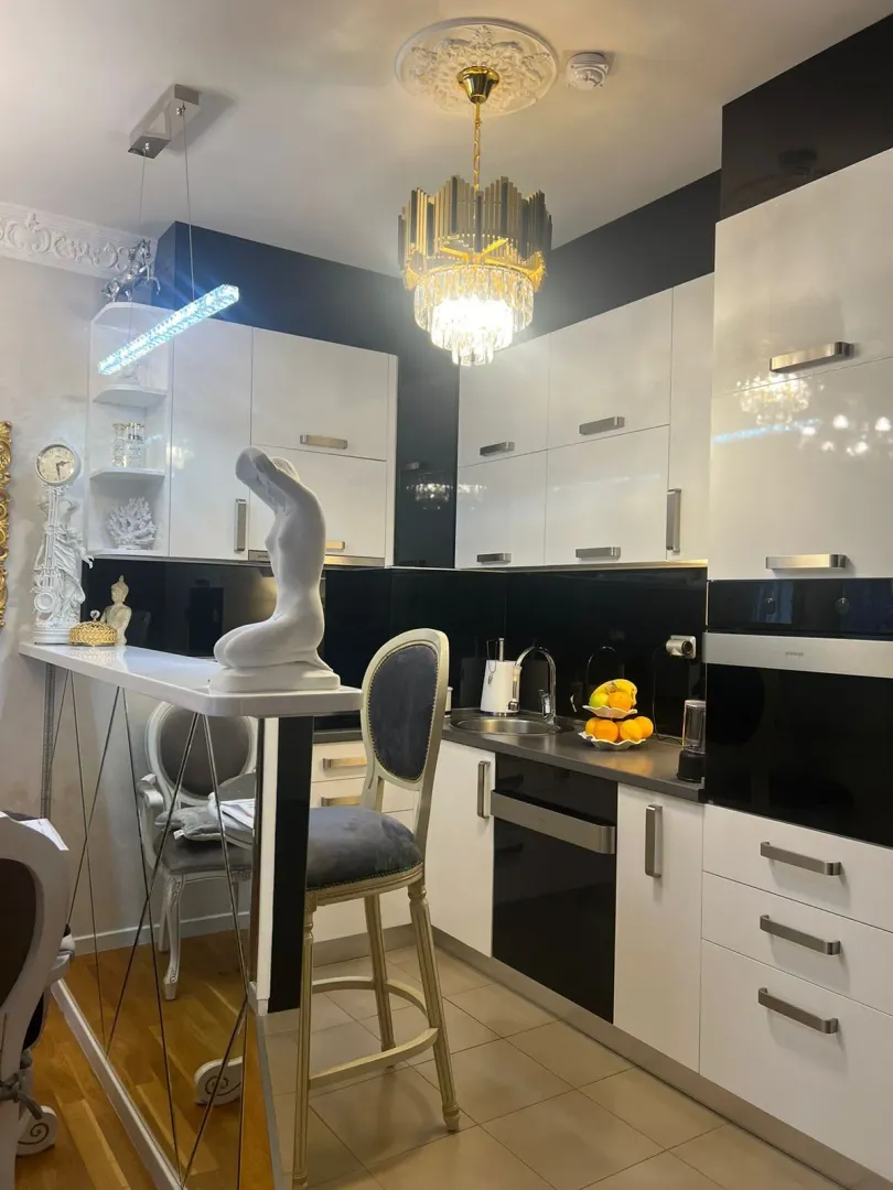 Moderna kuhinja sa šankom, trpezarijskim stolicama i elegantnim osvjetljenjem.