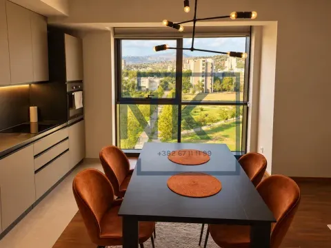 Dining area with a modern table and chairs next to the kitchen and a large window. - image 2