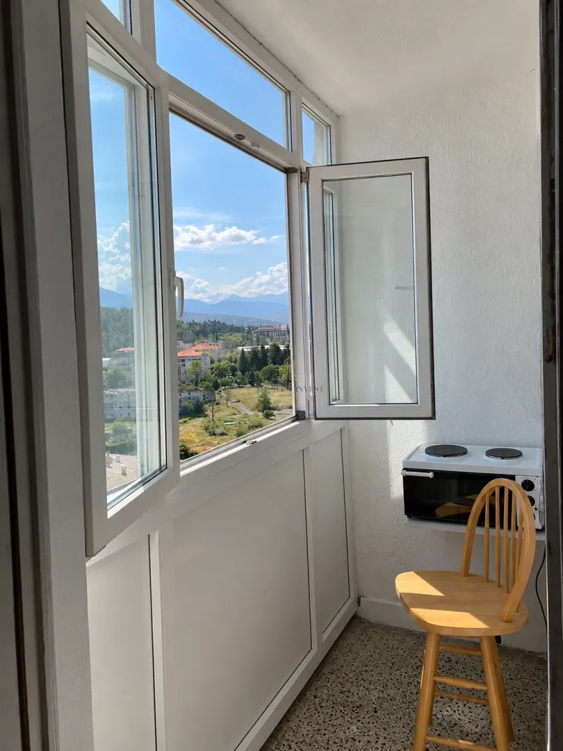 Zastakljeni balkon sa pogledom na okolinu i manjim šporetom.