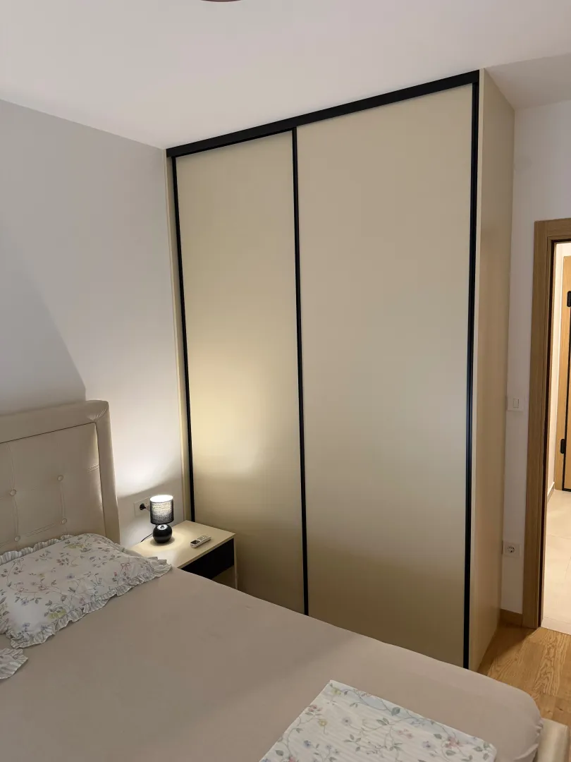 Furnished bedroom with a bed, wardrobe, and nightstand.
