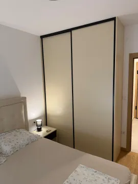 Furnished bedroom with a bed, wardrobe, and nightstand. - image 8