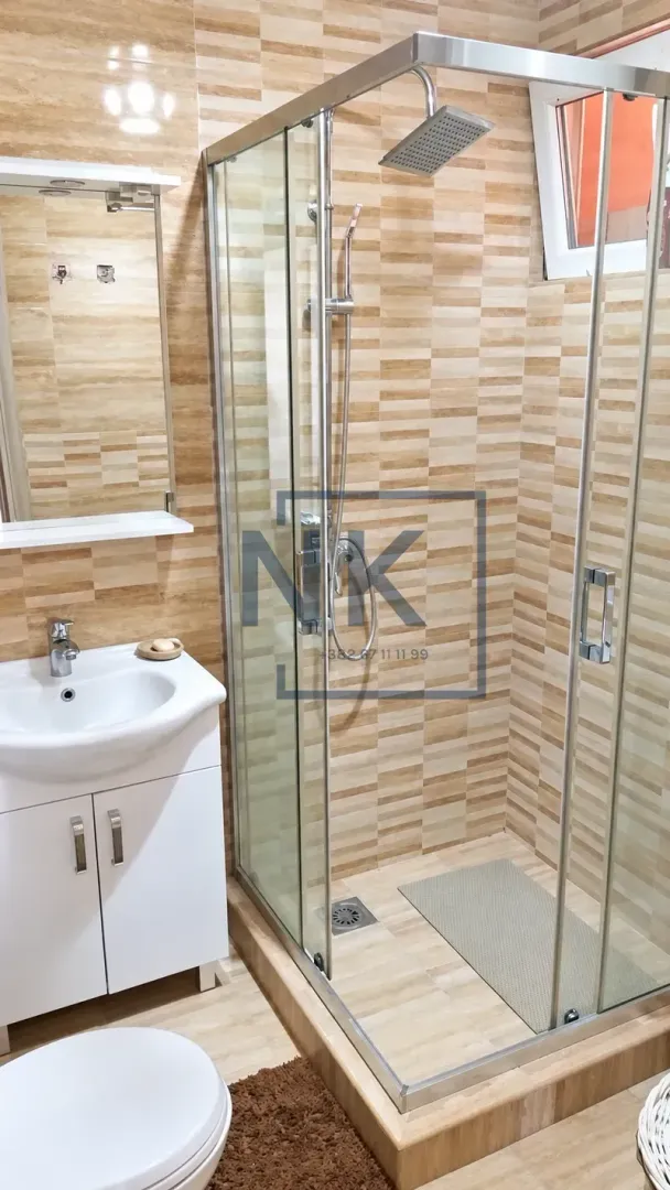 Bathroom equipped with a shower cabin, vanity with sink, and a mirror.