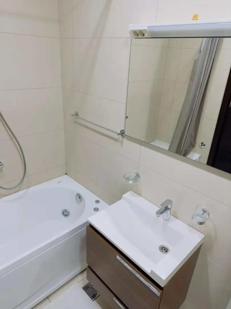 Kupatilo opremljeno kadom, umivaonikom sa ormarićem i ogledalom.