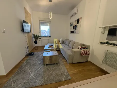 Uređena dnevna soba sa ugaonom garniturom, stočićem i televizorom na zidu. - image 2